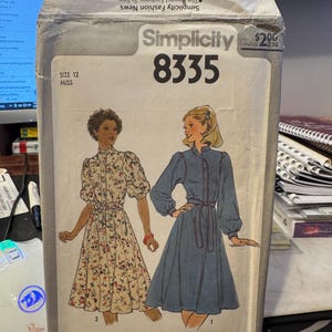 Puede incluir: Patrón de costura Simplicity número 8335 para un vestido. El patrón es para la talla 12 e incluye dos estilos de vestidos diferentes. Un vestido es de estampado floral y el otro es azul sólido. El patrón es de Simplicity Fashion News.