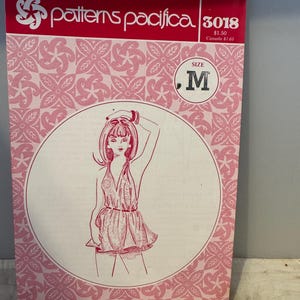 May include: A pink and white sewing pattern envelope with a drawing of a woman wearing a halter top and shorts. The pattern number is 3018 and the size is M.