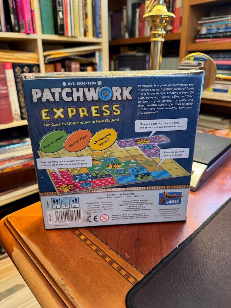 May include: A square board game box titled Patchwork Express by Uwe Rosenberg. The blue box features game instructions, colourful quilt tile illustrations, and text including Easy to Learn, Fast to Play, and Challenging Puzzle. It shows player counts, age ratings, and a barcode on the bottom edge.