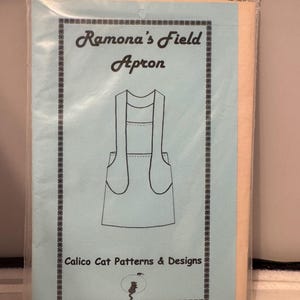 May include: A sewing pattern for a blue apron with a pocket. The pattern is titled "Ramona's Field Apron" and is from Calico Cat Patterns & Designs.