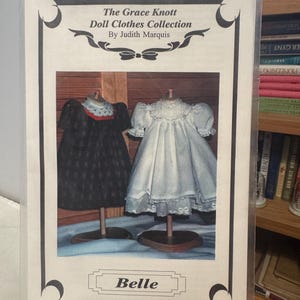 May include: A package featuring doll clothes patterns. The cover displays two doll dresses: one black with a white collar and one white with lace trim. The text reads "The Grace Knott Doll Clothes Collection" and "Belle."