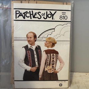 May include: A vintage sewing pattern for a vest, featuring a couple wearing vests with geometric patterns. The pattern is titled "Patches of Joy" and has the number 810. The pattern is from Joyce Kelly and is copyrighted 1980.