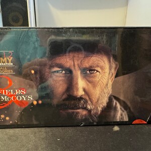 May include: A black and red DVD box with a close-up of a man's face. The text on the box reads "2012 Emmy Consideration in all categories Hatfields & McCoys."