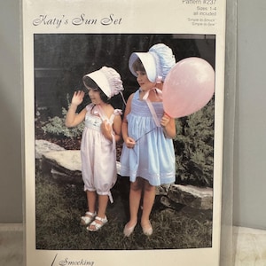 May include: A vintage sewing pattern for a children's sun set. The pattern is for sizes 1-4 and includes instructions for smocking and sewing. The pattern features two girls wearing matching dresses and bonnets. The girls are holding a pink balloon and standing in a garden setting.
