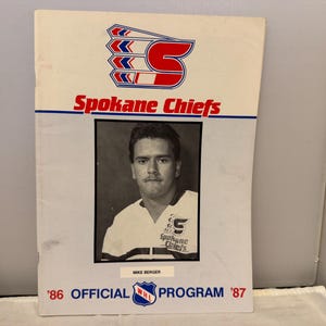 May include: A vintage Spokane Chiefs hockey program from 1987. The cover features the team logo in red, white, and blue, along with the text "Spokane Chiefs." A black and white photo of Mike Berger is in the center.