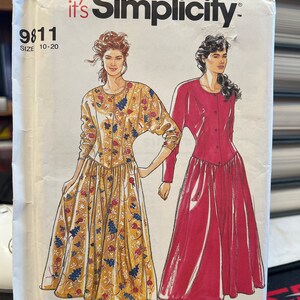 May include: Simplicity sewing pattern number 9811 for a dress, sizes 10-20. The pattern shows two models wearing the dress, one in a floral print and the other in a solid red.