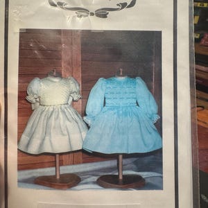 May include: A package featuring two doll dresses on stands. One dress is light blue, the other is a pale green. The package is labeled "The Grace Knott Doll Clothes Collection" and "The Princess Dress."
