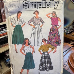 Może przedstawiać: Koperta z wykrojem krawieckim Simplicity przedstawiająca ilustracje pięciu różnych stylów spódnic. Wzory obejmują jednolitą zieloną spódnicę, białą spódnicę zapinaną na guziki z kieszeniami, spódnicę w kwiaty, ciemnozieloną spódnicę oraz spódnicę w kratę.