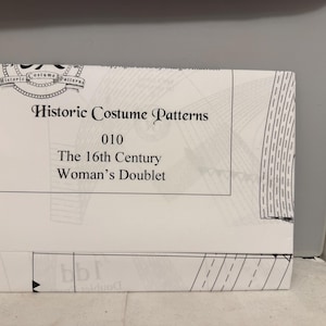 Könnte beinhalten: Ein weißes Papiermuster für ein Wams für Frauen aus dem 16. Jahrhundert. Das Muster stammt aus der Serie "Historic Costume Patterns" und trägt die Nummer 010. Das Cover zeigt ein dekoratives Emblem und detaillierte Illustrationen.