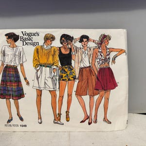 May include: Vogue's Basic Design pattern 1549. The image shows illustrations of five different outfits, including shorts, skirts, and tops. The outfits are in various colors, including white, yellow, black, brown, and red. The pattern is for women's clothing.