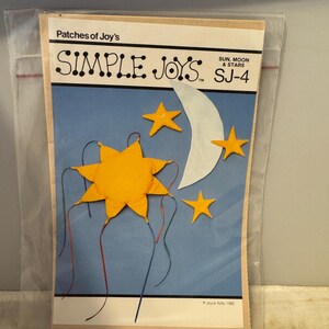 Könnte beinhalten: Ein Bastelmuster für die Herstellung eines Mobiles mit Sonne, Mond und Sternen. Das Muster heißt "Simple Joys" und stammt von Patches of Joy's. Die Musternummer ist SJ-4.