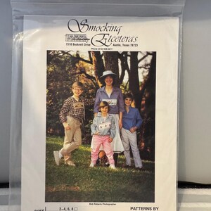Puede incluir: Una familia de cuatro personas posa para una foto en un área boscosa. La familia lleva ropa informal. La imagen incluye el texto "Smocking Etceteras" y "Patterns by Natalie Green".