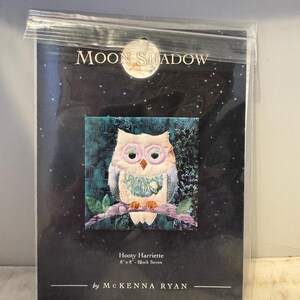Może przedstawiać: Wzór do patchworku dla bloku o nazwie "Hooty Harriette" przedstawiający białą sowę z różowymi akcentami siedzącą na gałęzi. Wzór ma 20,3 cm na 20,3 cm i jest częścią kolekcji "Moon Shadow" autorstwa Mckenny Ryan.