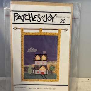 May include: A craft pattern for a wall hanging titled "Patches of Joy" Calico Cottage 20. The pattern features a colorful applique design of a house with a red door and yellow windows. The pattern is for a 20 inch by 26 inch wall hanging.