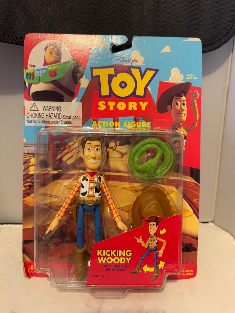 May include: A Toy Story "Kicking Woody" action figure in its original packaging. The packaging features Woody, a green snake, and a cowboy hat. The text on the packaging reads "Toy Story Action Figure" and "Kicking Woody with Kicking Leg Action".