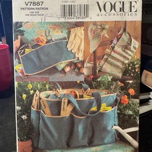 Op de afbeelding: Een Vogue Accessories naaipatroon voor een tuintas en een gereedschapshouder voor in de tuin. Het patroonnummer is V7887. De tuintas is tealblauw met bruine afwerking en heeft meerdere vakken. De gereedschapshouder is blauw met een bloemenprint en heeft een bruine band.