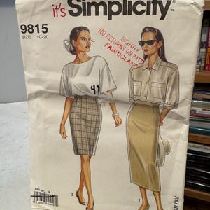 Puede incluir: Un patrón de costura Simplicity vintage, talla 10-20, con ilustraciones de dos mujeres con faldas y blusas. La portada del patrón es blanquecina con el texto "it's Simplicity" y "9815".