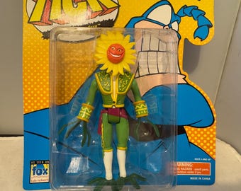 May include: A vintage action figure of a character with a sunflower head and a green matador-style outfit. The figure is in a clear plastic package with a blue and yellow Fox Kids Network backing card. The packaging includes the text "AGES 4 AND UP".