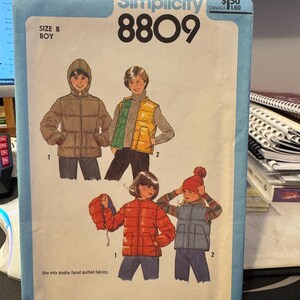May include: Simplicity sewing pattern number 8809 for a boy's quilted jacket and vest. The pattern includes instructions for two different styles of jackets and vests, one with a hood and one without. The pattern is for size 8.