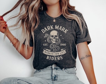 May include: A dark gray t-shirt with a graphic print of a skull and snake with the text "Dark Mark Est. 1990 Marked for Life Riders".