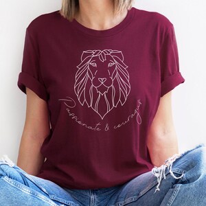 May include: A maroon t-shirt with a white outline of a lion's head and the text "Passionate & Courageous" underneath.