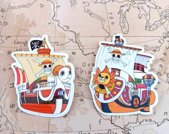 May include: Two die-cut vinyl stickers featuring pirate ships from the anime One Piece. The left sticker shows the Going Merry with a ram figurehead, while the right sticker depicts the Thousand Sunny with a lion figurehead and a number one.