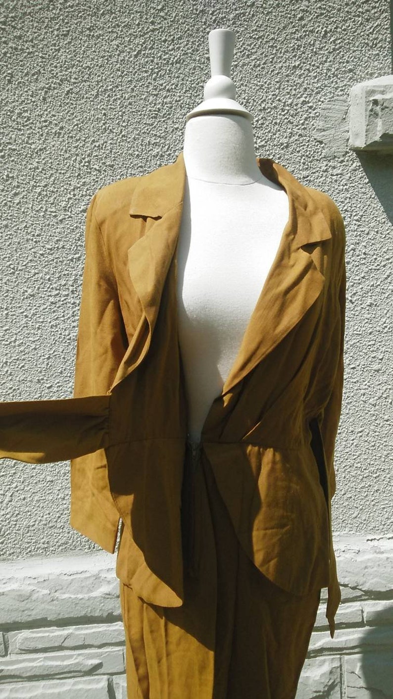May include: A brown wrap dress with a long sleeve and a deep V-neckline. The dress is made of a soft, flowing fabric and has a cinched waist.