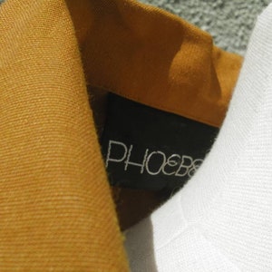 May include: Close-up of a brown corduroy collar with a black label that says "PHOEBE" in white lettering.