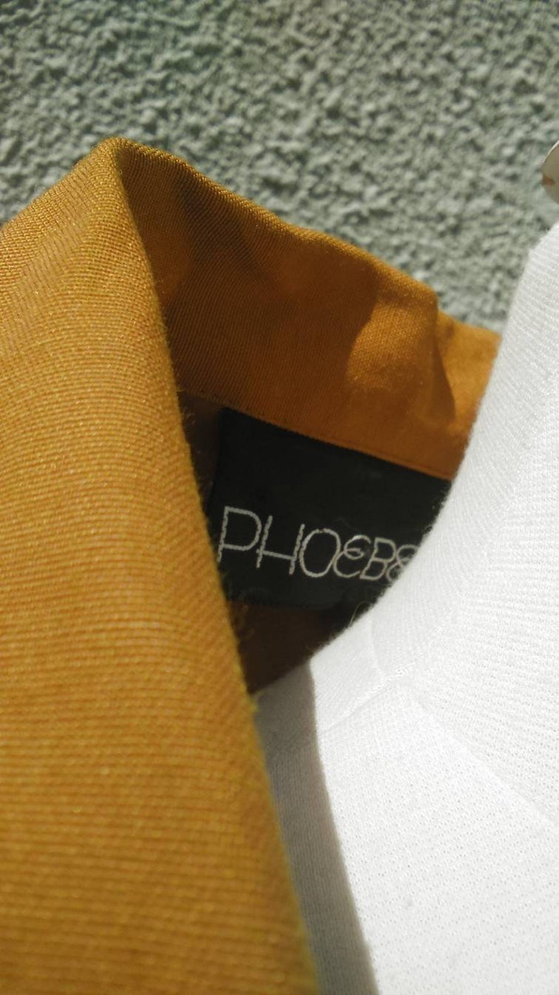 May include: Close-up of a brown corduroy collar with a black label that says "PHOEBE" in white lettering.