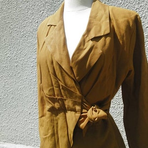 May include: A brown wrap dress with a long sleeve and a tie at the waist.