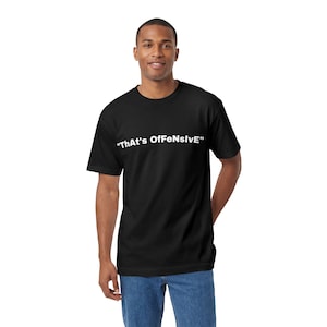 May include: Black t-shirt with the white text "ThAt's OfFeNsIvE". The shirt is a classic crew neck style. The person in the image is wearing blue jeans.