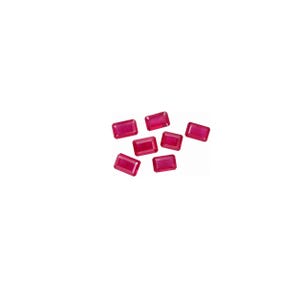 Peut inclure: Un ensemble de sept pierres précieuses en vrac, d'un rose rougeâtre vif, chacune taillée en forme d'émeraude rectangulaire avec des surfaces facettées qui reflètent la lumière. Les pierres sont disposées en grappe éparse, montrant leur couleur et leur clarté uniformes.
