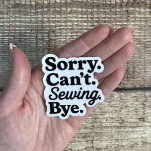 May include: A white die-cut sticker with a black border and bold black text that reads Sorry. Can't. Sewing. Bye. The sticker features a rounded, organic shape and is presented against a neutral background to highlight the clear, legible typography.