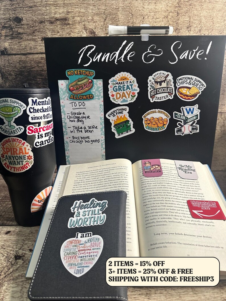 May include: A collection of stickers, a tumbler, a notebook, and an open book. The stickers have various designs and phrases, including "Make it a Great Day" and "Emotional Support Chips & Queso." The tumbler has stickers. The notebook says "Healing & Still Worthy."