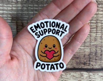 May include: A die-cut sticker featuring a cartoon brown potato with a smiling face, rosy cheeks, and small arms holding a red heart. The text EMOTIONAL SUPPORT POTATO is printed in bold black capital letters above and below the potato character.