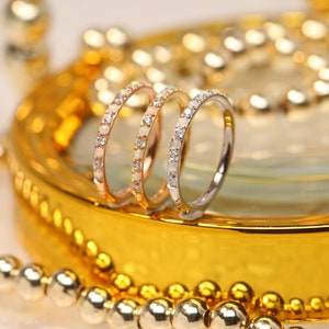 Puede incluir: Dos anillos de plata y oro rosa con ópalos y piedras transparentes engastados en pavé. Los anillos están sobre una superficie dorada.