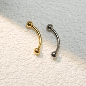 May include: Two curved barbell earrings, one gold and one silver, with ball ends.
