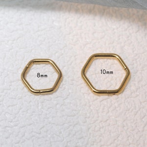 Könnte beinhalten: Zwei goldene sechseckige Creolen, eine mit einem Durchmesser von 8 mm und die andere mit einem Durchmesser von 10 mm.