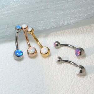 May include: Four belly button rings with opal stones. The rings are in silver, rose gold, gold, and titanium. The opal stones are white with a rainbow sheen.