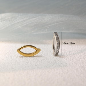 May include: Two gold and silver hoop earrings with clear gemstones. The silver hoop earring is 10mm/12mm in diameter.