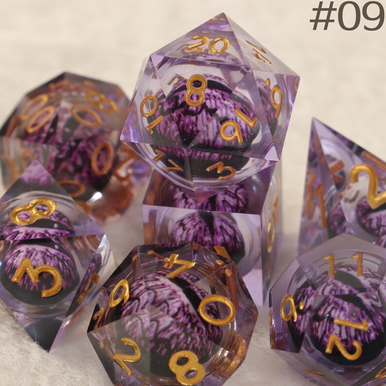 K&ouml;nnte beinhalten: Eine Sammlung klarer, vielseitiger W&uuml;rfel mit einem lila-schwarzen Innendesign. Die Zahlen sind goldfarben. Die W&uuml;rfel sind in einer Gruppe angeordnet, mit dem Text "#09" in der oberen rechten Ecke.