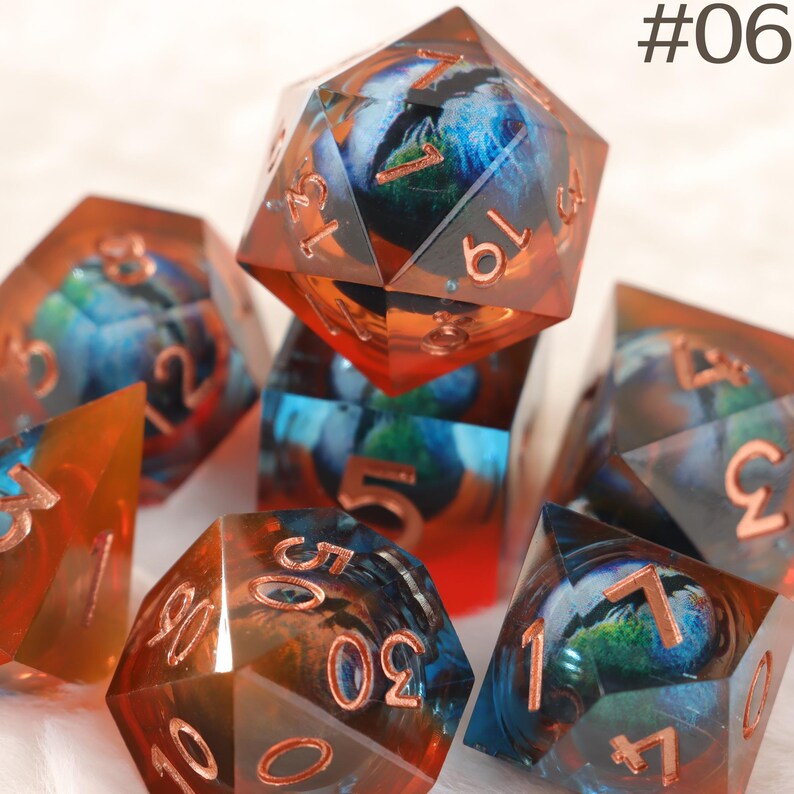 K&ouml;nnte beinhalten: Satz von Polyederw&uuml;rfeln mit einem einzigartigen Design. Die W&uuml;rfel sind transparent mit einer Mischung aus Blau, Orange und Rot. Jeder W&uuml;rfel hat kupferfarbene Zahlen. Das Bild enth&auml;lt den Text "#06".