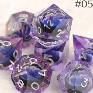 K&ouml;nnte beinhalten: Set aus sieben polyedrischen W&uuml;rfeln mit einem lila-blauen Galaxiemuster. Die W&uuml;rfel haben silberne Zahlen und bestehen aus klarem Harz. Das Bild enth&auml;lt den Text "#05".