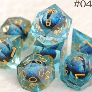 K&ouml;nnte beinhalten: Ein Satz polyedrischer W&uuml;rfel in Blau und Gold. Die transparenten W&uuml;rfel haben ein blaues Design im Inneren und goldene Zahlen. Das Bild enth&auml;lt den Text "#04".