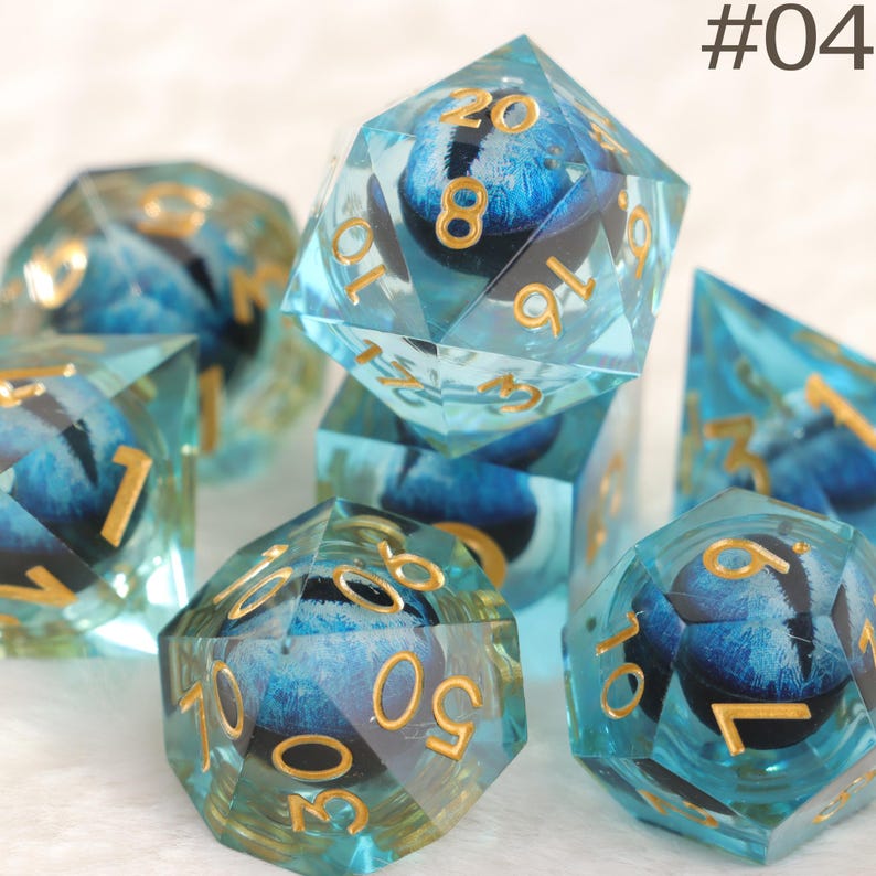 K&ouml;nnte beinhalten: Ein Satz polyedrischer W&uuml;rfel in Blau und Gold. Die transparenten W&uuml;rfel haben ein blaues Design im Inneren und goldene Zahlen. Das Bild enth&auml;lt den Text "#04".