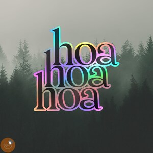 May include: A holographic sticker featuring the word "hoa" repeated three times in a stacked, vertical arrangement. The lettering displays a shifting spectrum of iridescent colours, including pink, blue, and yellow, against a dark background.
