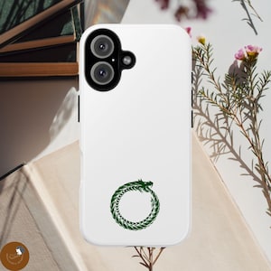 Könnte beinhalten: Eine weiße Smartphone-Hülle mit einer dunkelgrünen Ouroboros-Grafik in der Mitte. Die Hülle verfügt über ein schwarzes Kameramodul mit zwei kreisförmigen Linsen und einem kleinen Blitz, das sich in der oberen linken Ecke des Geräts befindet.