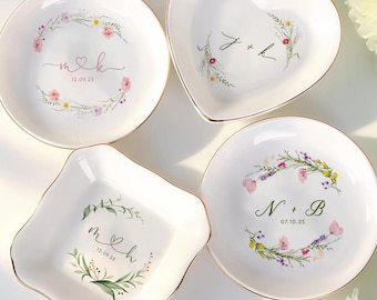 May include: Four white ceramic dishes in different shapes, each with a gold rim and floral design. The dishes feature initials and dates, perfect for wedding or anniversary gifts.