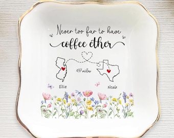 May include: A white ceramic trinket dish with a gold rim, featuring a floral design and the text "Never too far to have coffee ether." The dish includes illustrations of the states of New Jersey and Texas, connected by a dotted line and a heart.