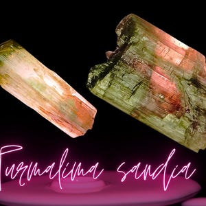 Op de afbeelding: Twee groene, roze en bruine toermalijnkristallen. De kristallen zijn ruw en hebben een ruwe textuur. De kristallen bevinden zich op een zwarte achtergrond.